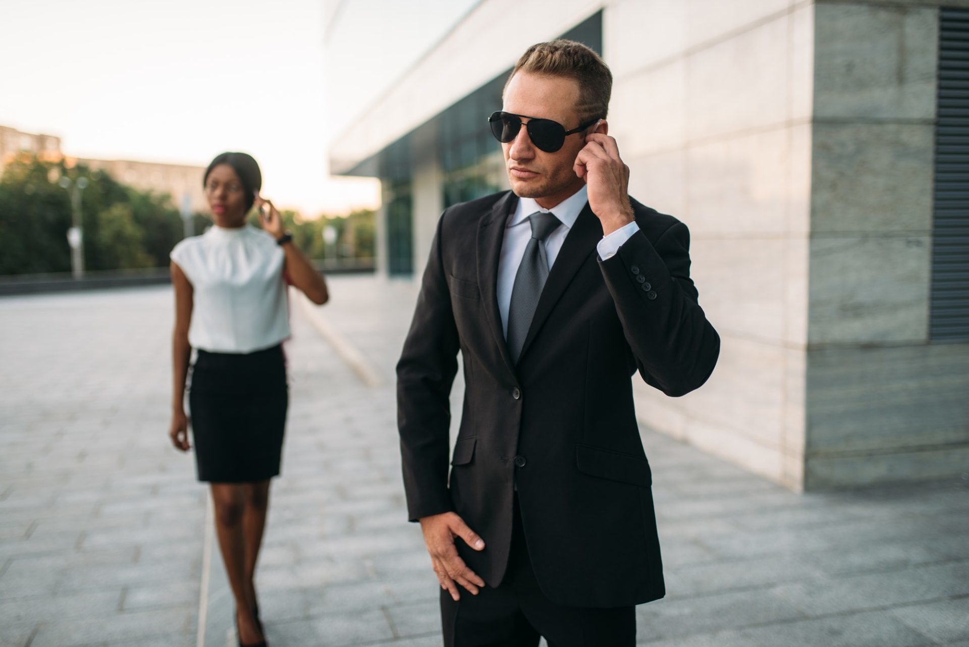 bodyguard opening car door for businessman and listening security earpiece bodyguard opening car door for businessman and listening security earpiece